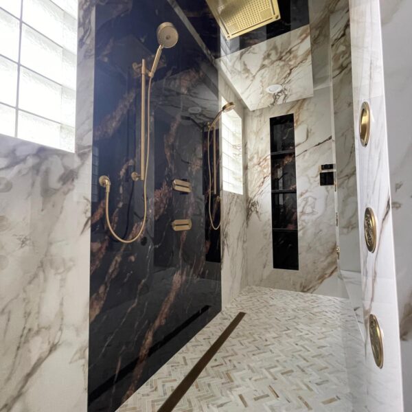 Sleek bathroom remodel featuring black marble and gold accents done by The Woodlands Premier Remodeling