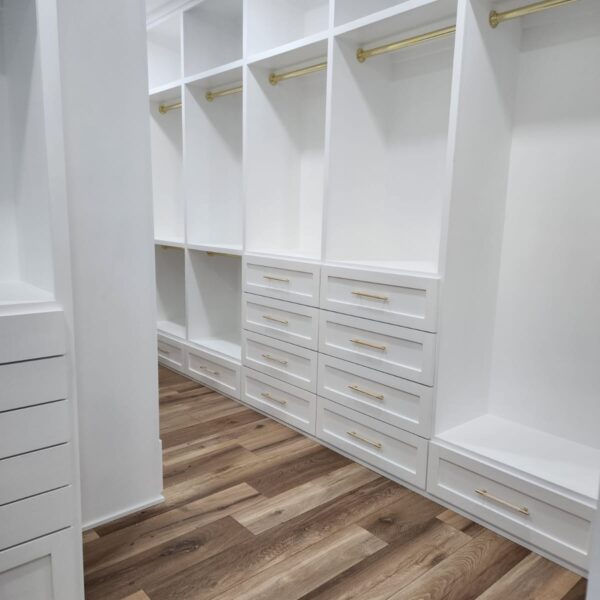 The Woodlands Premier Remodeling after photo of custom primary closet with custom white cabinets and hanging space