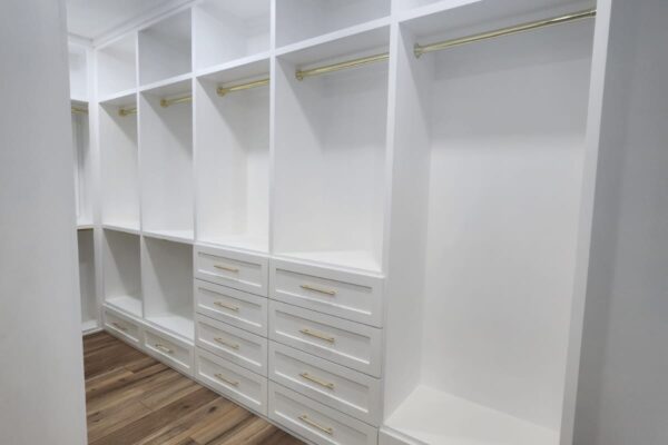 The Woodlands Premier Remodeling after photo of custom primary closet with custom white cabinets and hanging space