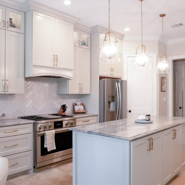 Bright white kitchen with pendent lights and marble countertops