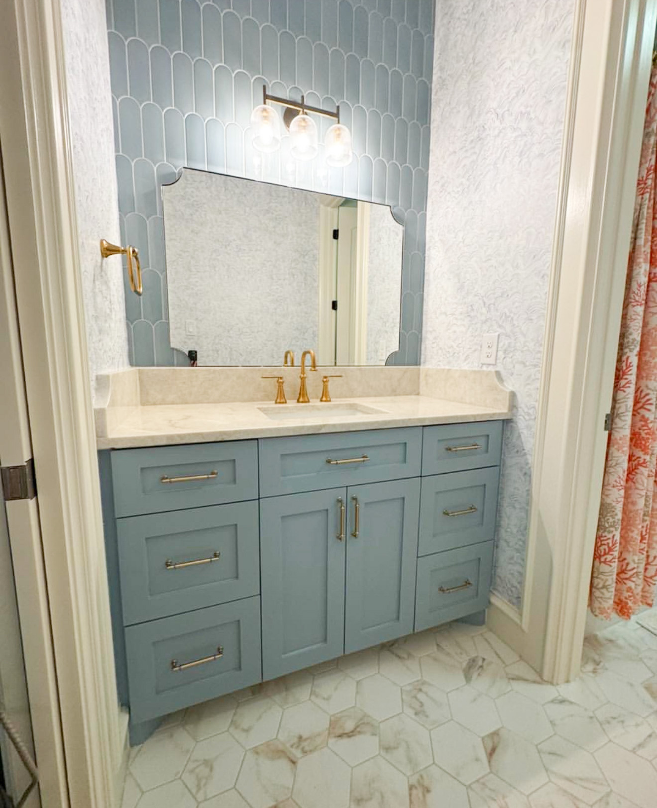 Blue cabinetry with wallpaper in a bathroom remodel by The Woodlands Premier Remodeling