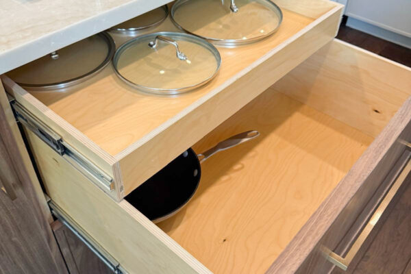 Two kitchen drawers are open. Both drawers are built into a wooden cabinet under a light countertop. Remodel done by The Woodlands Premier Remodel in The Woodlands, TX.